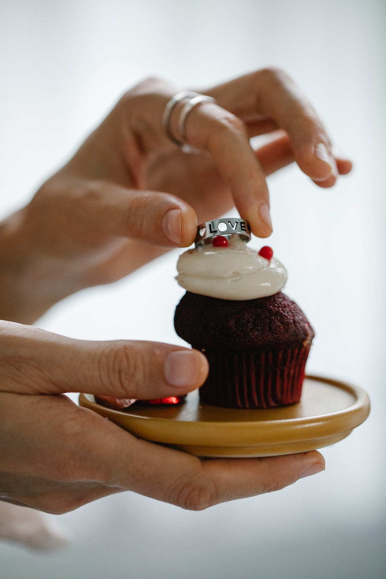 female hands holding an engraved, silver ring on a chocolate cupcake